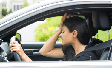 woman holding head while driving a vehicle
