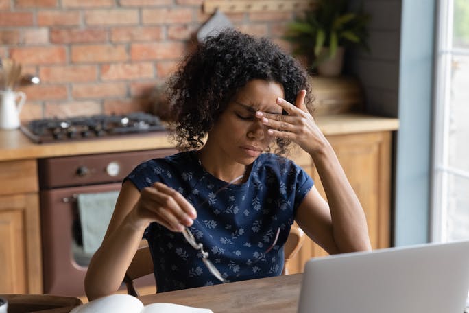 Woman sitting at computer struggles with migraine