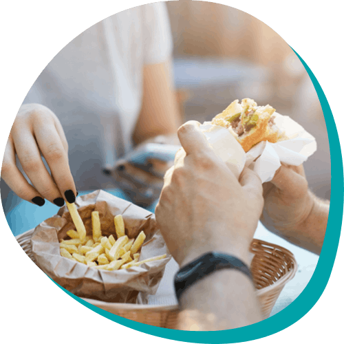 zoomed up image of the hands of two people eating hamburgers and french fries