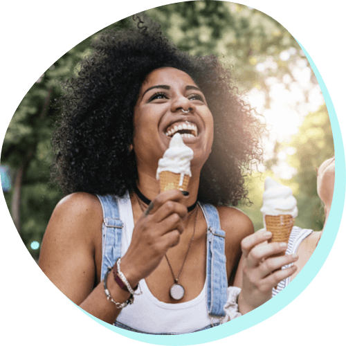 young woman laughing with a melting ice cream cone in her hand