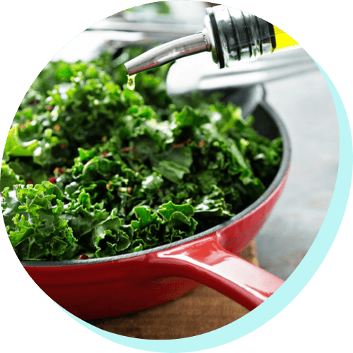 image of a red cast-iron skillet cooking fresh bright green kale
