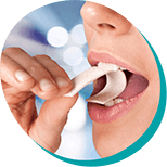 close up of a woman taking a bite out of a strip of gum