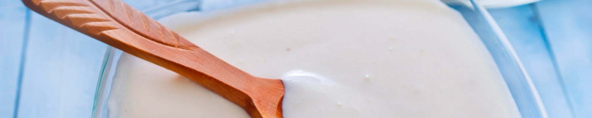   Syrnet melk i en skål, med en tresleiv oppi (avlangt)
