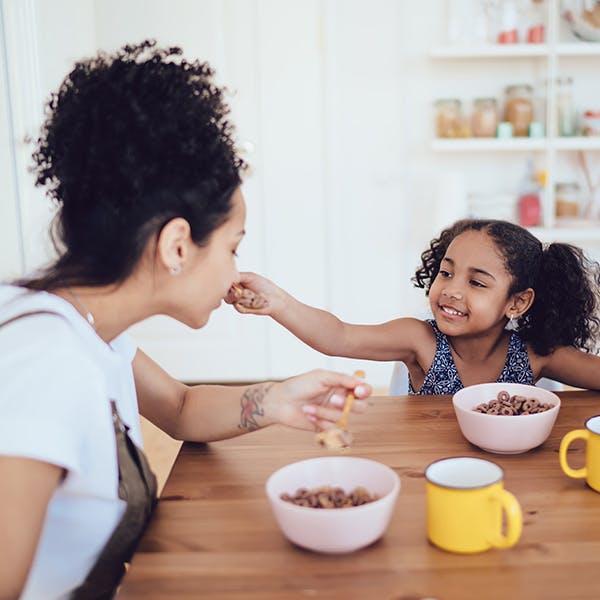 Kvinde og hendes datter spiser morgenmadsprodukter sammen