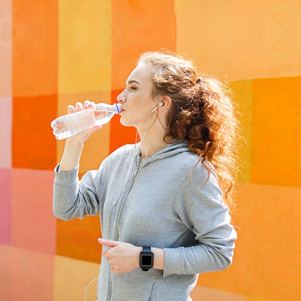Ung kvinde drikker flaske vand