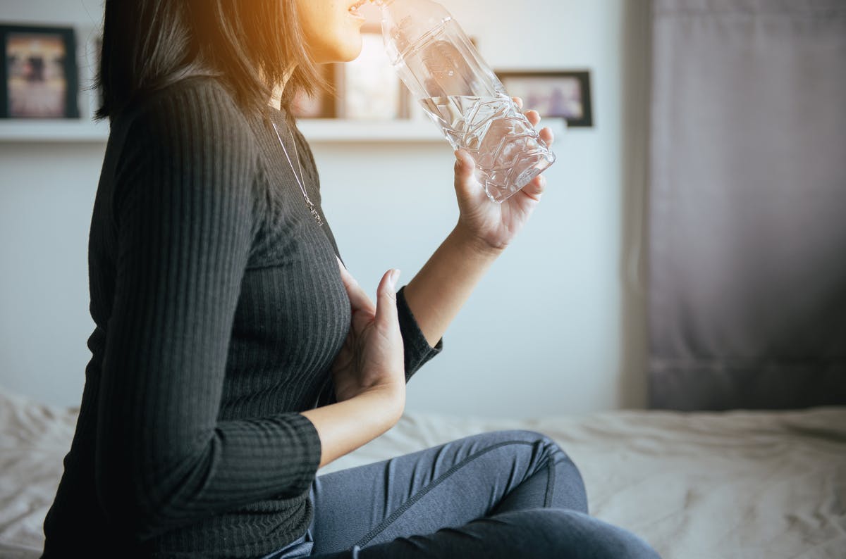 Woman drinking water to soothe heartburn