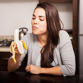 Mujer comiéndose un plátano amarillo