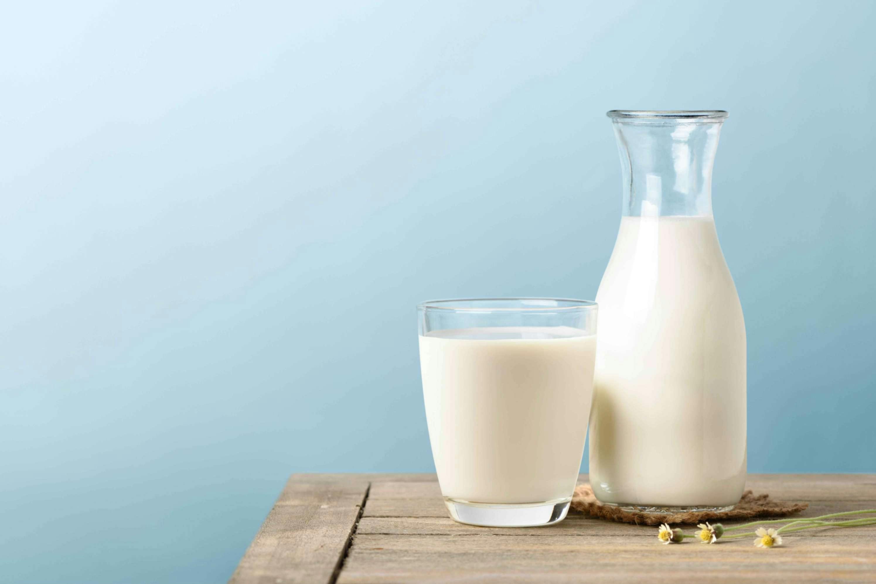 Vaso de leche y botella de leche sobre una mesa de madera