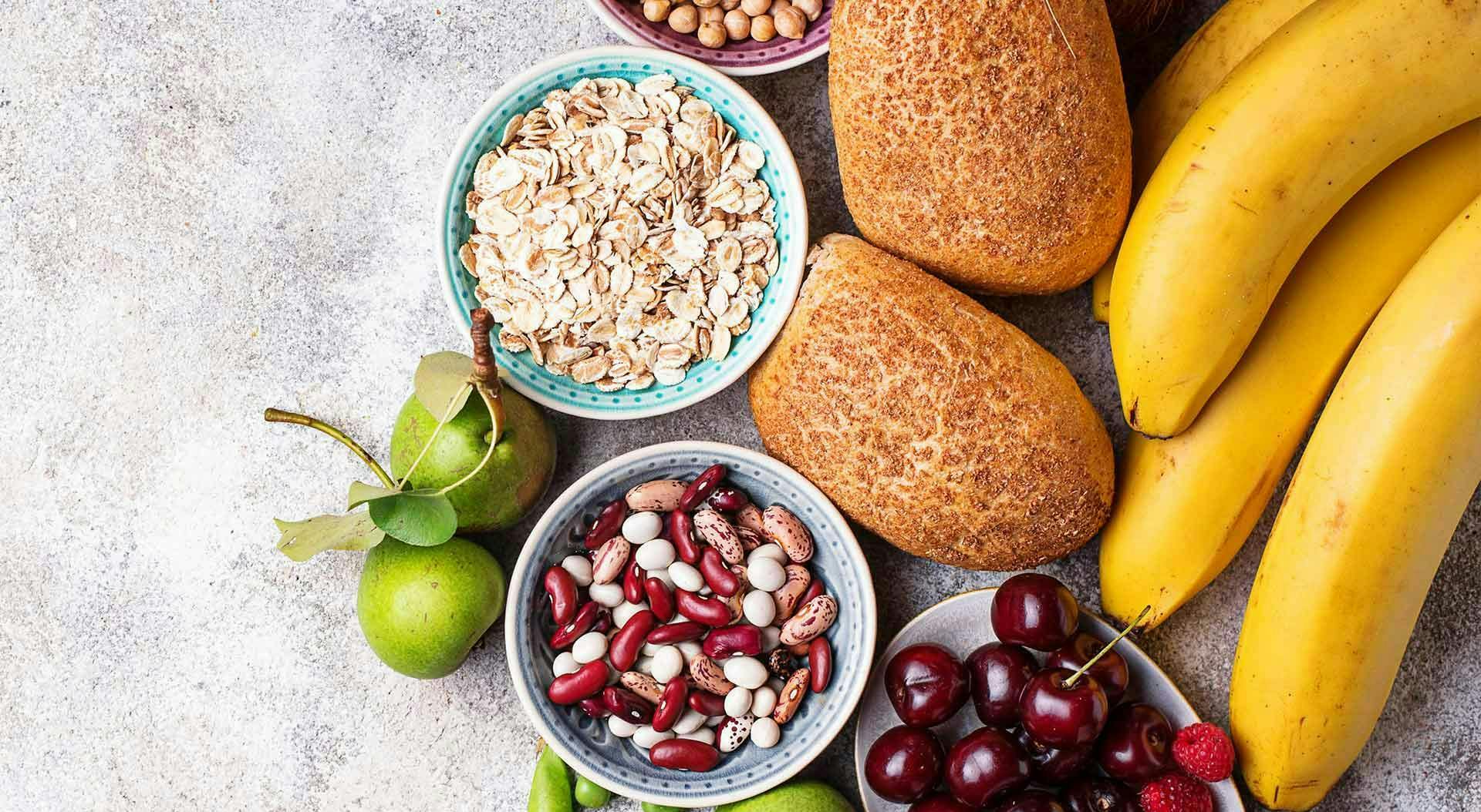 Varios alimentos ricos en fibra están agrupados sobre un fondo de mármol gris.