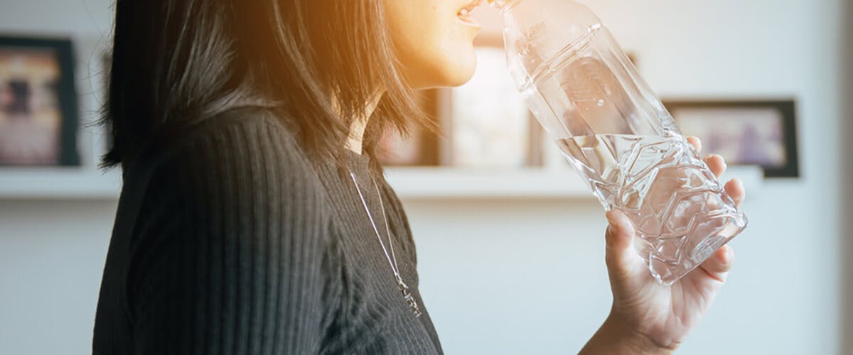 Mujer tomando agua para aliviar la acidez