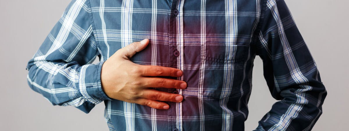 Hombre sosteniéndose el pecho con síntomas de sensación de ardor