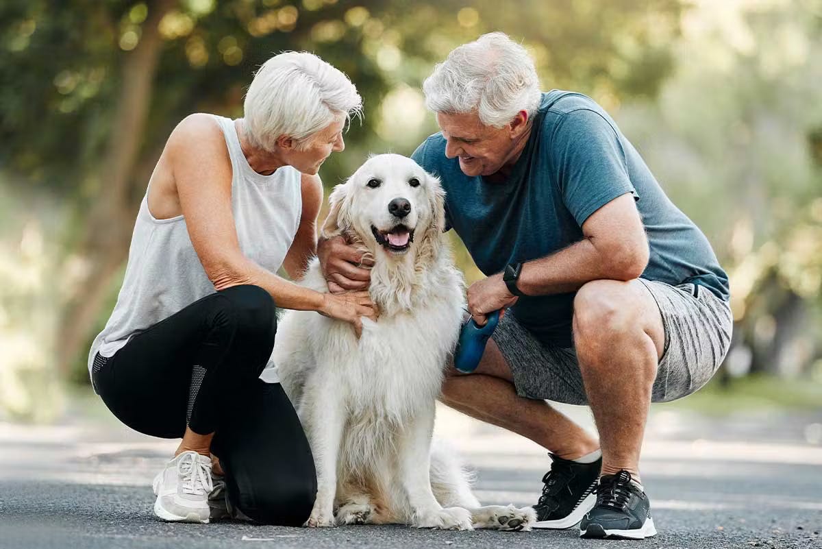 Pareja de ancianos paseando juntos a su perro