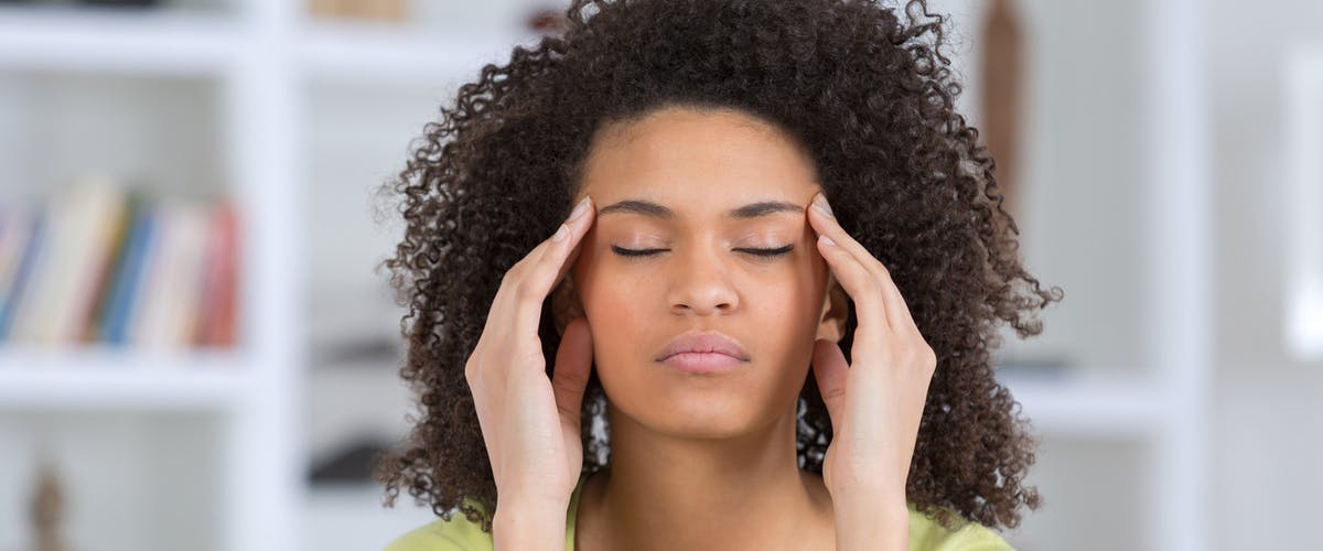 Acid Reflux and Anxiety Young stressed woman with eyes closed and hands on her temples
