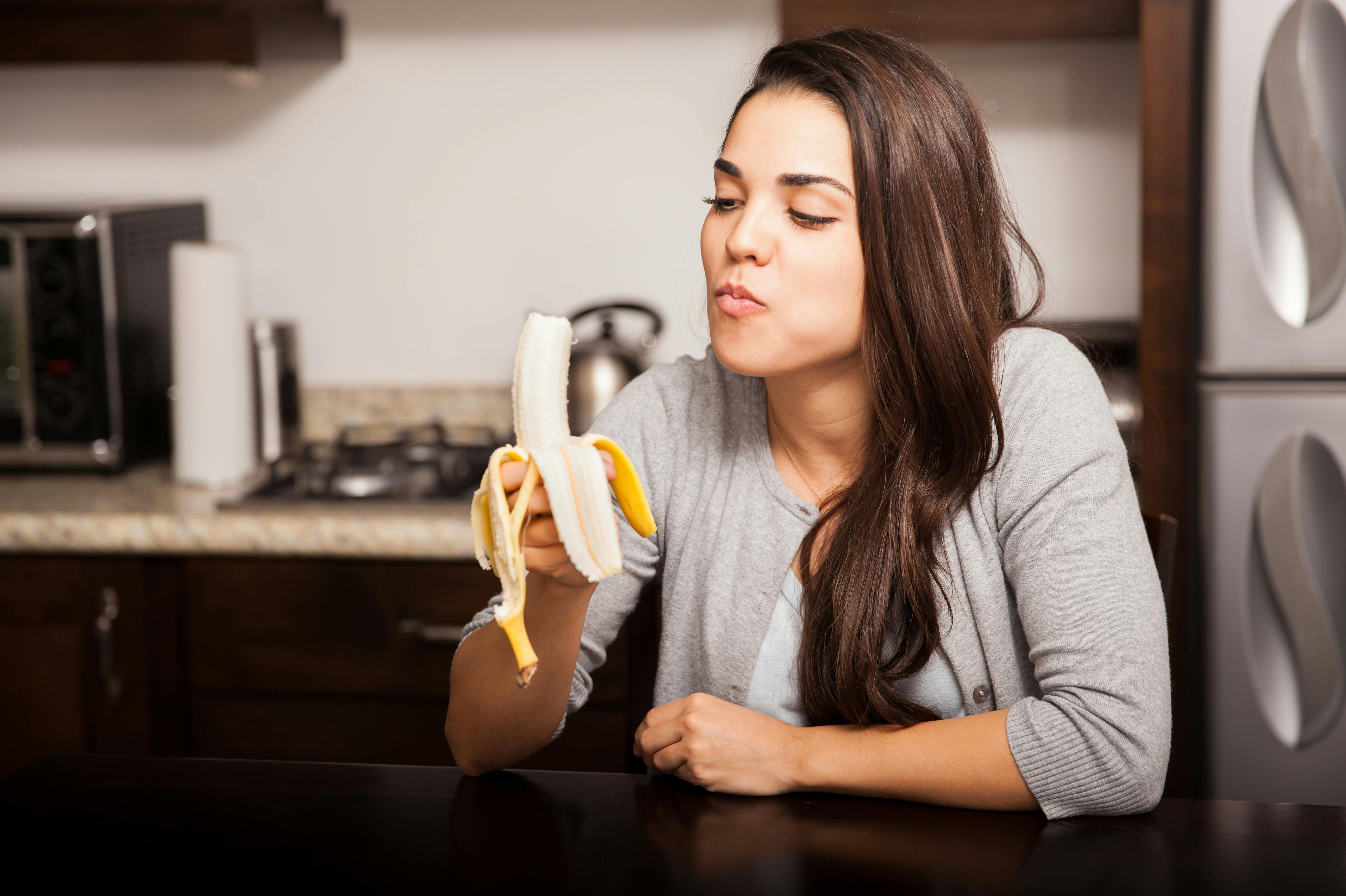 a woman eating a yellow banana