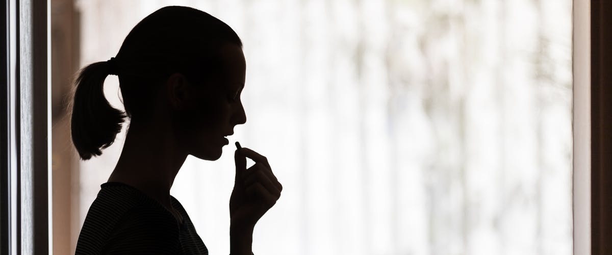 Woman taking pill in shadow 