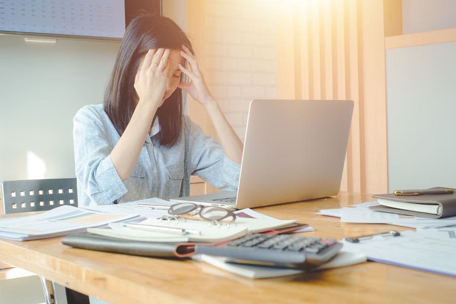 Stressed woman sitting at desk in front of laptop with head in her hands Stressed woman sitting at desk in front of laptop with head in her hands