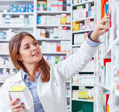 Pharmacist checking stock in aisle at drugstore 
