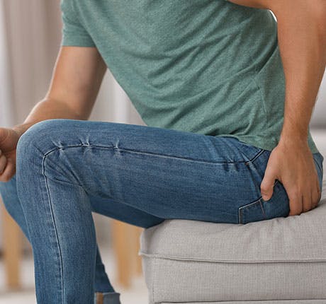 Man on couch with hemorrhoid pain