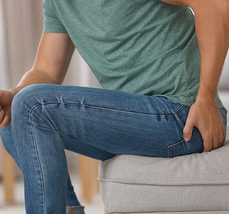 Man on couch with hemorrhoid pain Man on couch with hemorrhoid pain