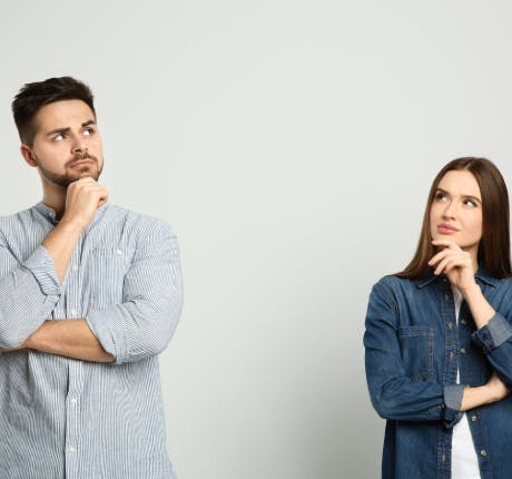 Couple on grey background looking pensive