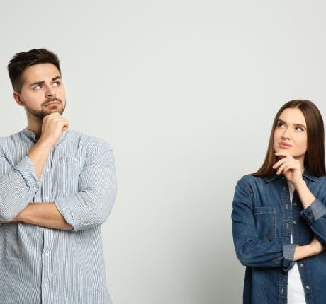 Couple on grey background looking pensive Couple on grey background looking pensive