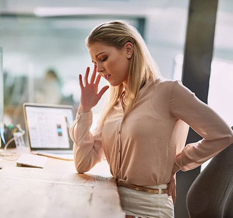 Woman sitting at desk looking uncomfortable Woman sitting at desk looking uncomfortable