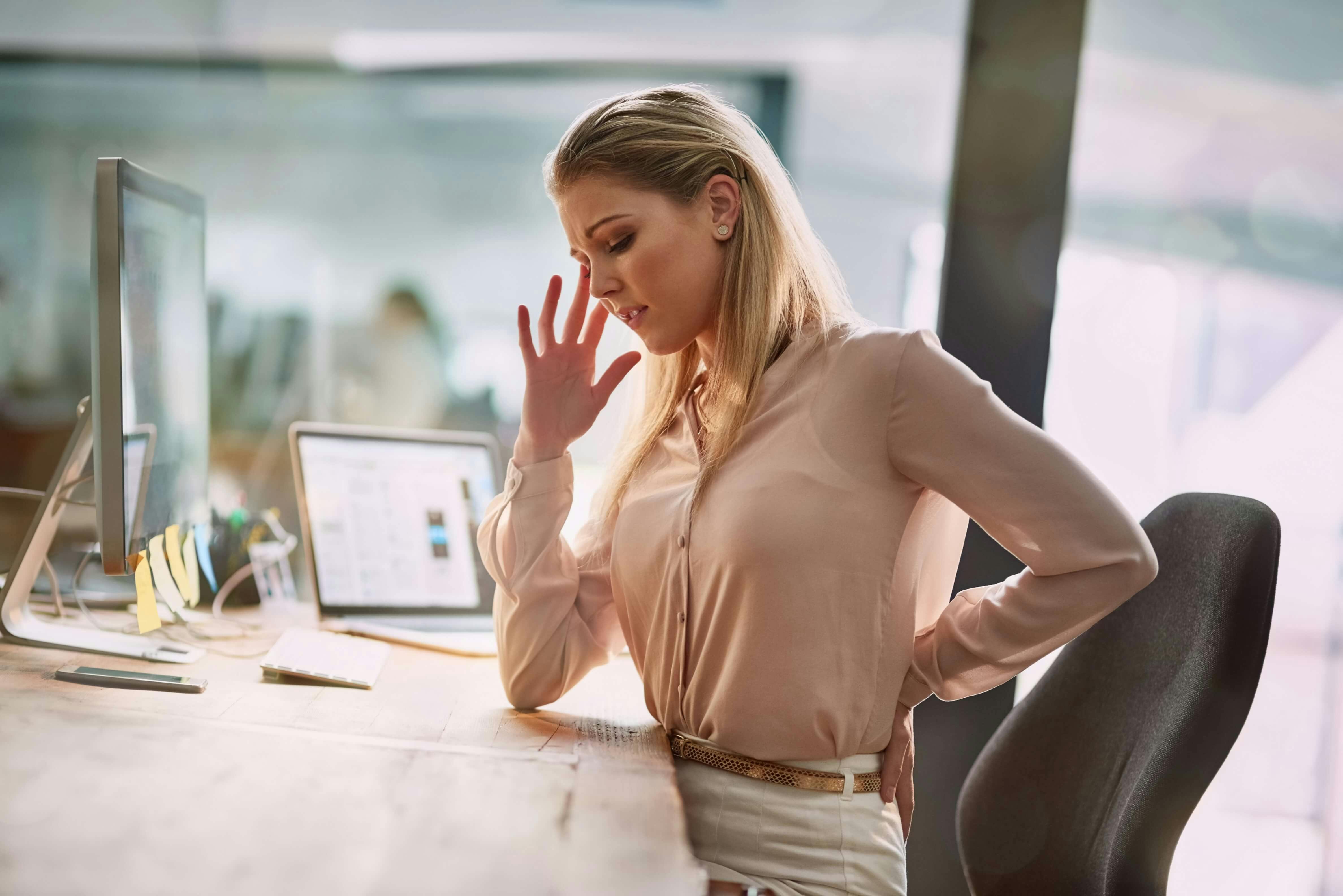 Woman sitting at desk looking uncomfortable Woman sitting at desk looking uncomfortable