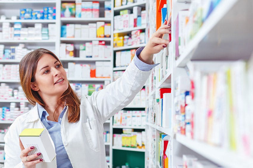 Pharmacist checking stock in aisle at drugstore Pharmacist checking stock in aisle at drugstore