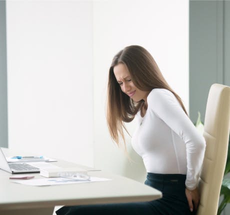 Businesswoman working in a chair looking uncomfortable Businesswoman working in a chair looking uncomfortable