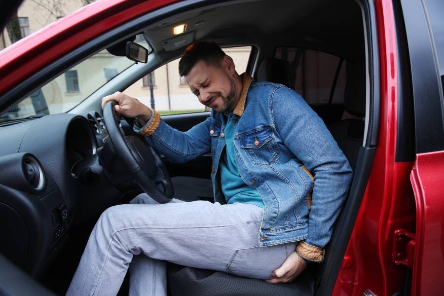 Man suffering from hemorrhoid pain in car Man suffering from hemorrhoid pain in car