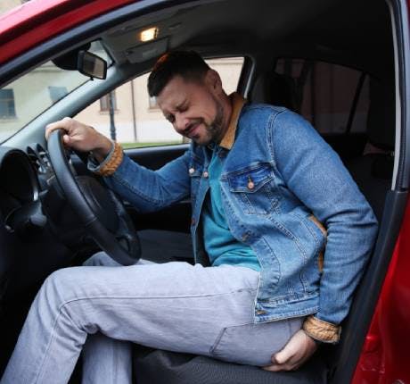Man suffering from hemorrhoid pain in car Man suffering from hemorrhoid pain in car