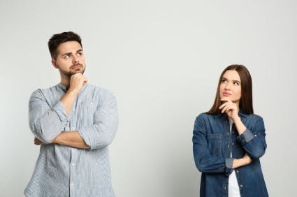 Couple on grey background looking pensive