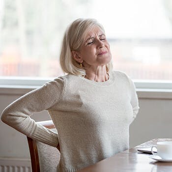 Person holding their back pain