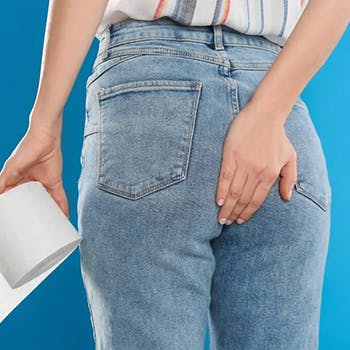 Woman with hemorrhoid holding toilet paper