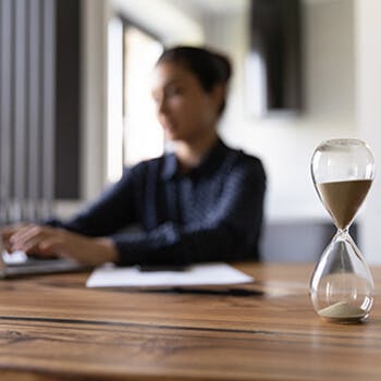 Persona que trabaja en la computadora portátil junto al reloj de arena