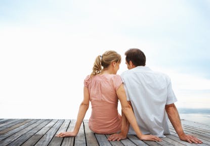 Couple sitting on a jetty with the sky as the background