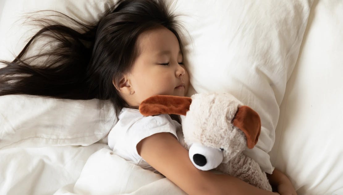 Child with stuffed animal sleeping in bed