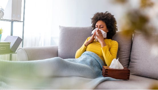 Woman suffering from allergies sneezes into a tissue