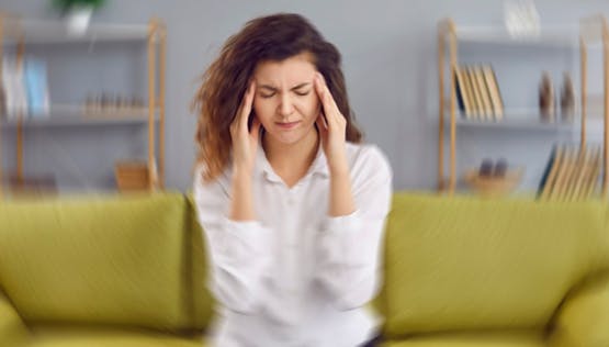 Woman sitting on couch suffering from dizziness