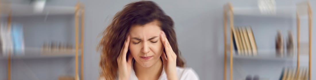 Woman sitting on couch suffering from dizziness