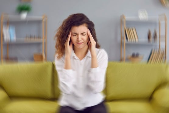 Woman sitting on couch suffering from dizziness