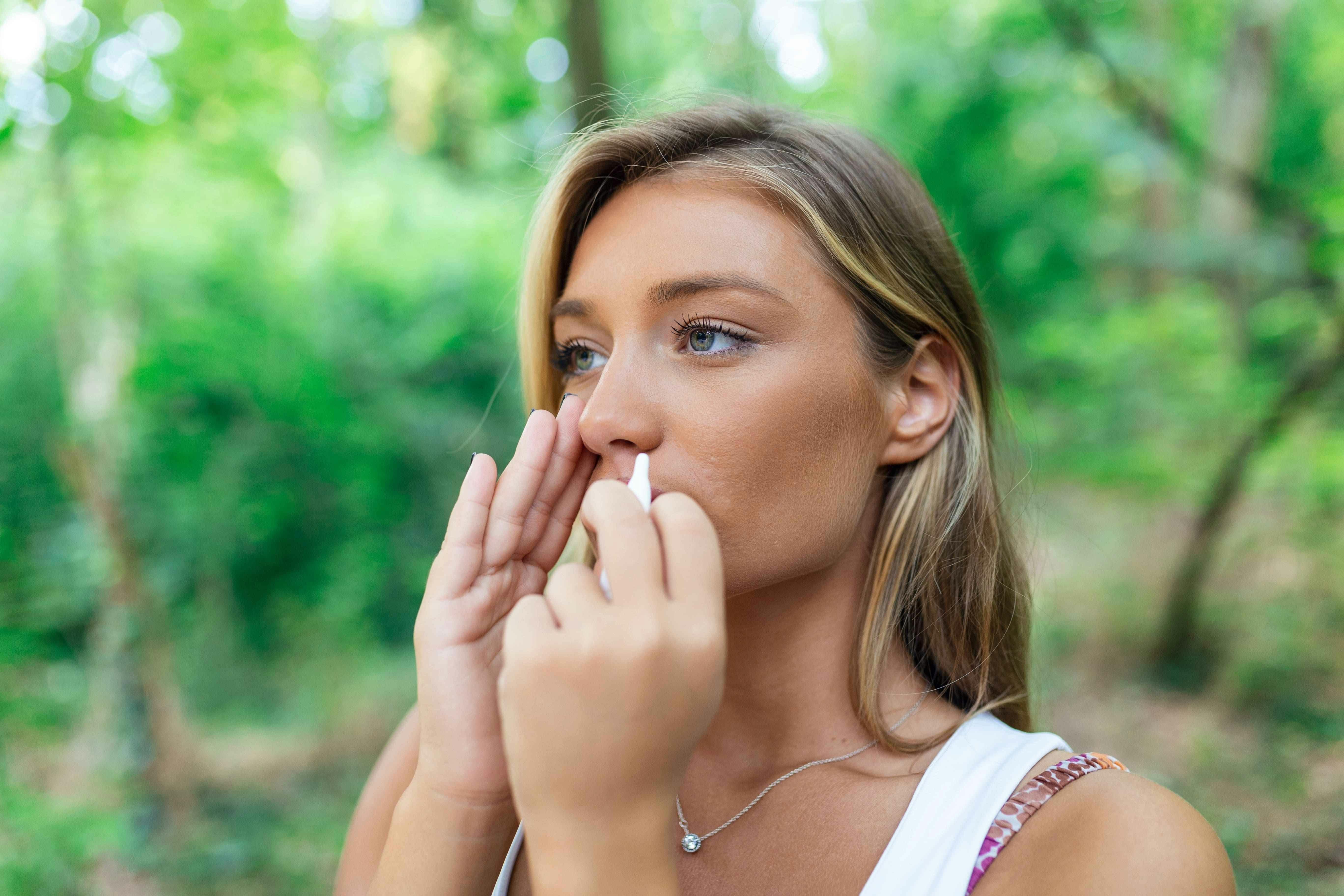 Woman using nasal spray outside