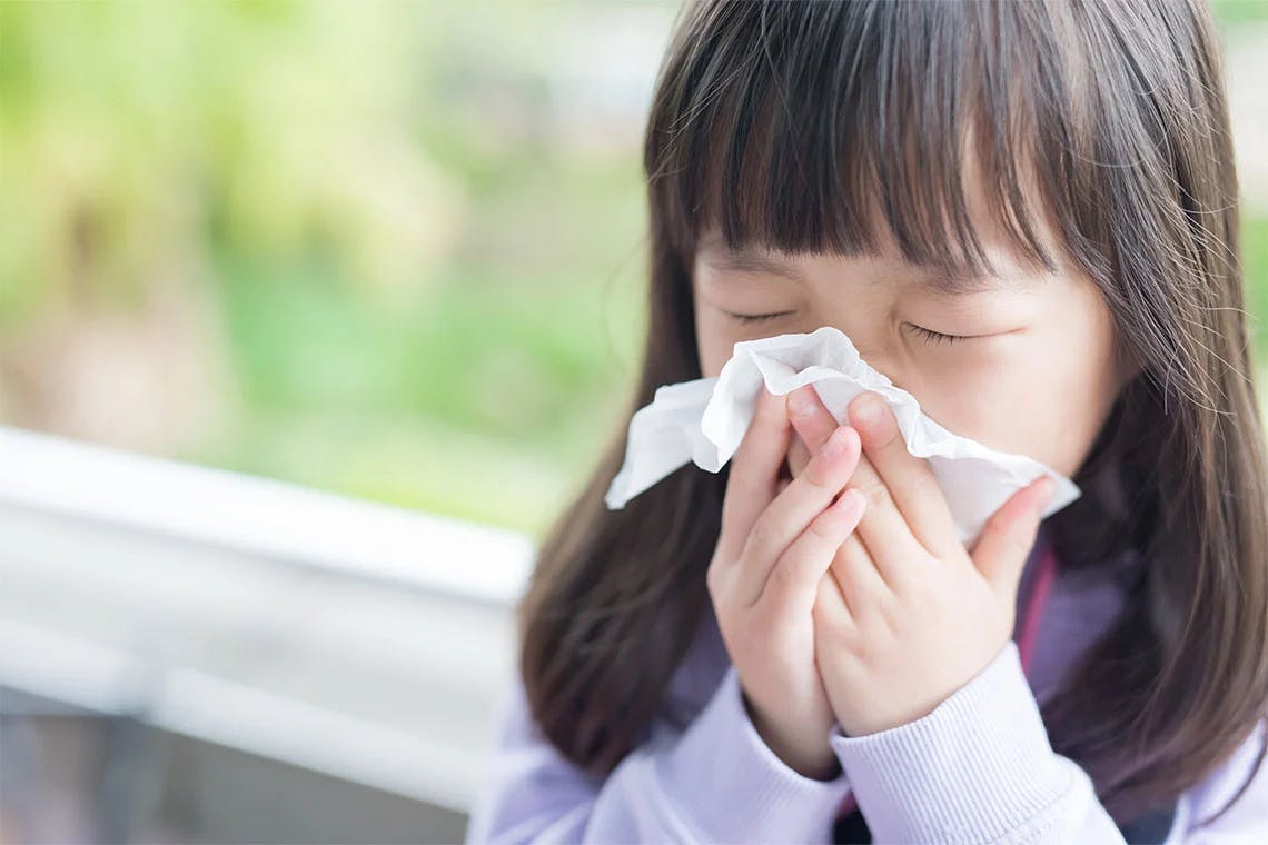 Young girl blowing her nose