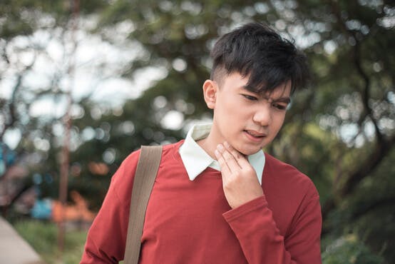 Man holding hand to throat