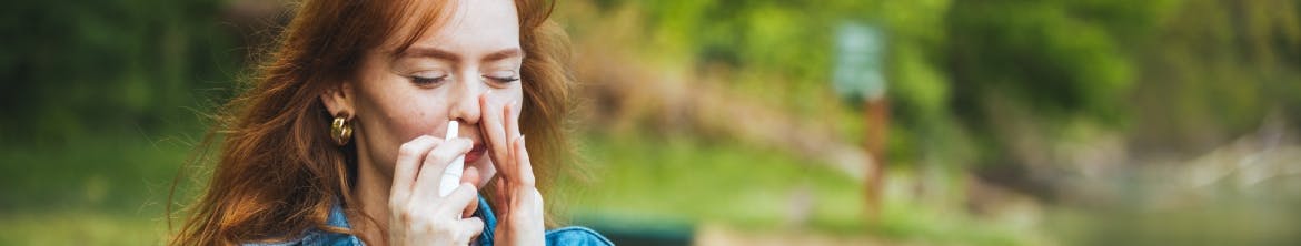 Woman using a nasal spray outside