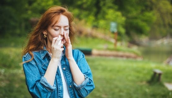 Woman using a nasal spray outside