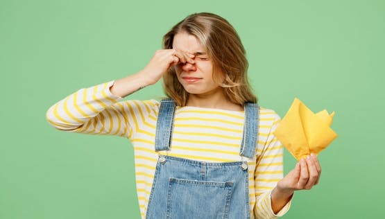 A women in a overalls and yellow striped shirt experiencing allergies