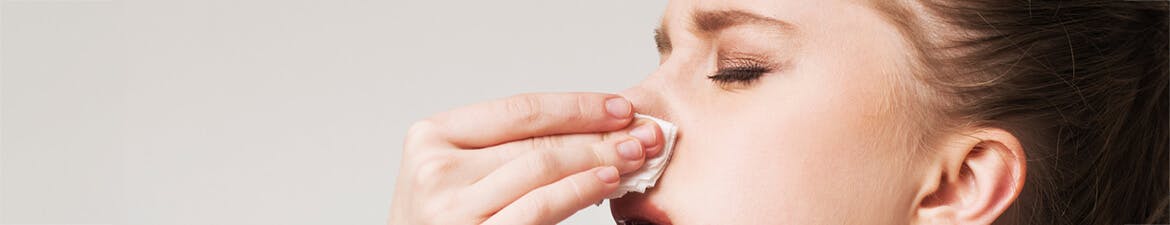 Woman holding tissue to nose