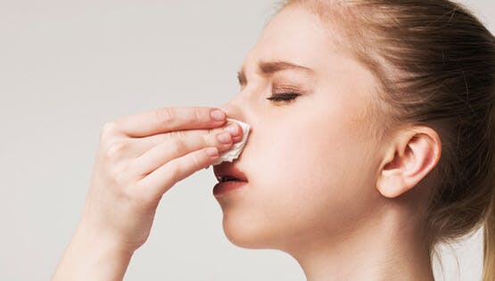 Woman holding tissue to nose