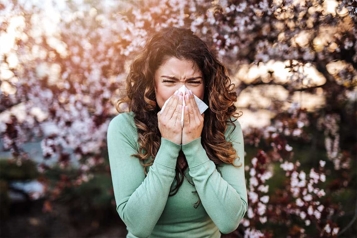 Woman blowing nose outside